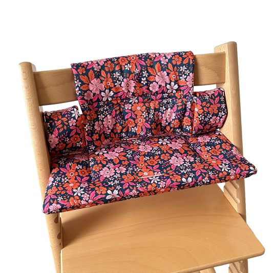 Kussenset voor Stokke Tripp Trapp met bloemenprint (oranje, roze). Zijaanzicht van het kussen op de stoel zonder gebruik van de babyset.