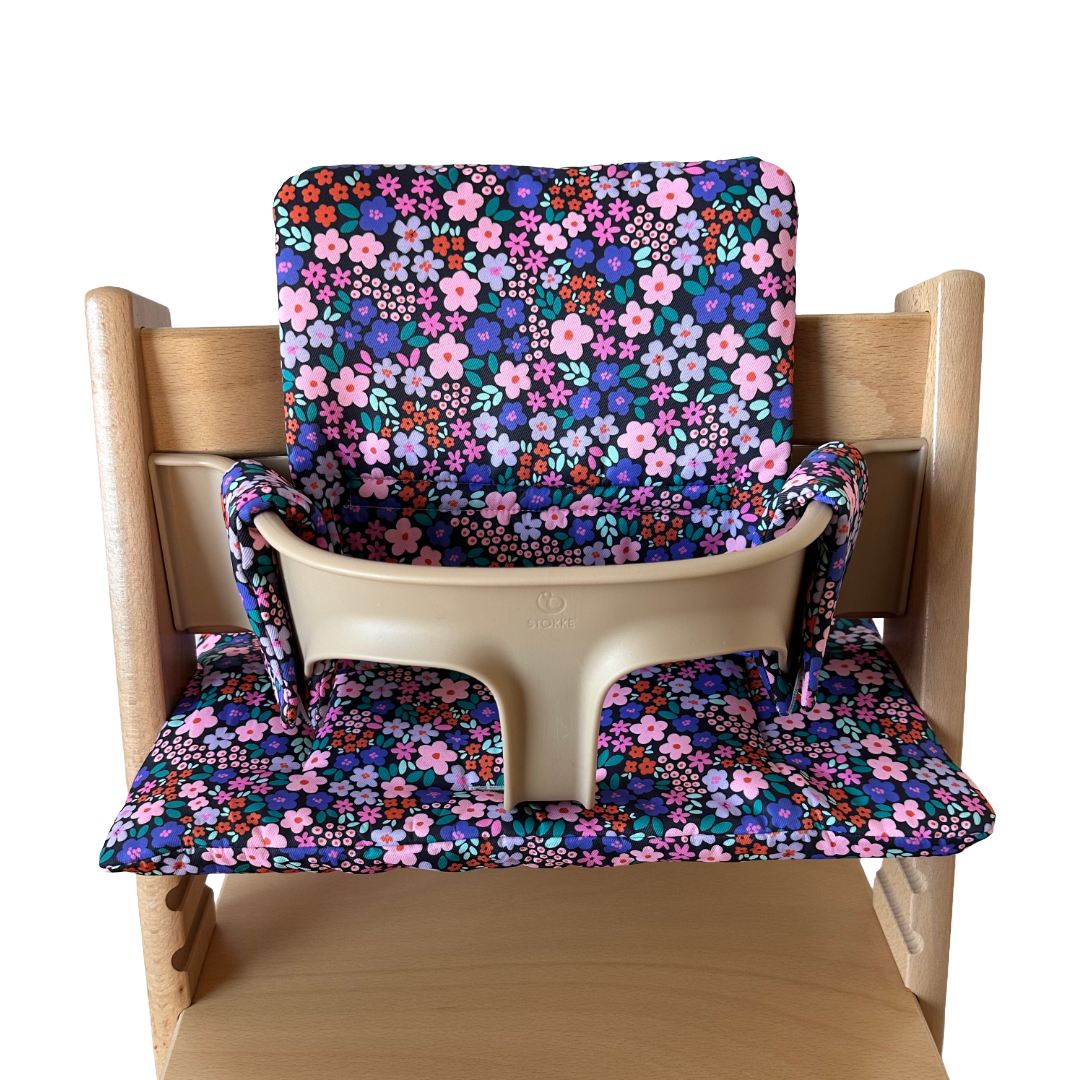 Kussenset voor Stokke Tripp Trapp met bloemenprint (paars, roze). Vooraanzicht van het kussen op de stoel met gebruik van de babyset.