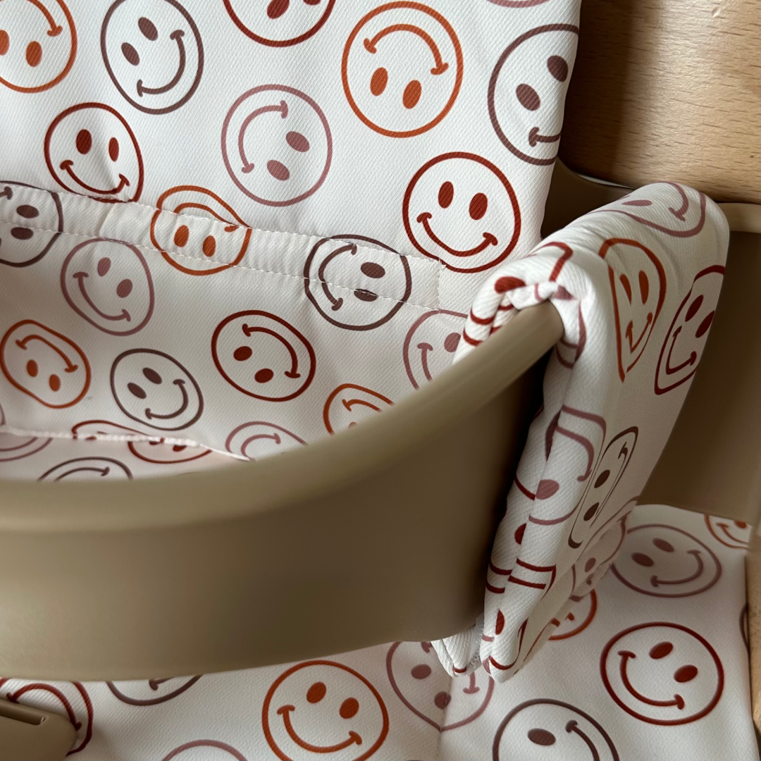 Kussenset voor Stokke Tripp Trapp met smileys patroon. Close up van het kussen op de stoel met gebruik van de babyset.
