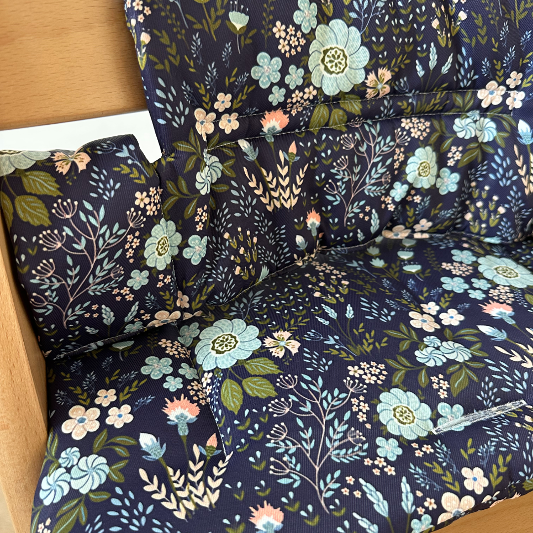 Kussenset voor Stokke Tripp Trapp met bloemenprint (blauw). Close up van het kussen op de stoel met gebruik van de babyset.
