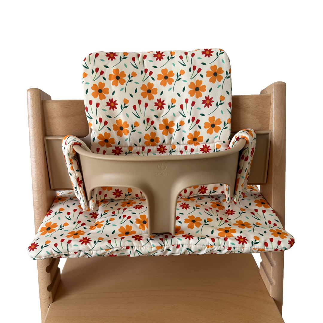 Kussenset voor Stokke Tripp Trapp met bloemenprint (oranje, rood). Vooraanzicht van het kussen op de stoel met gebruik van de babyset.