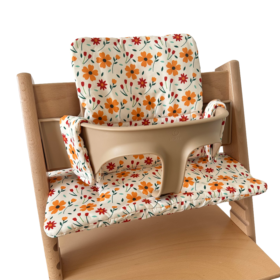 Kussenset voor Stokke Tripp Trapp met bloemenprint (oranje, rood). Zijaanzicht van het kussen op de stoel met gebruik van de babyset.