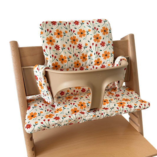 Kussenset voor Stokke Tripp Trapp met bloemenprint (oranje, rood). Zijaanzicht van het kussen op de stoel met gebruik van de babyset.