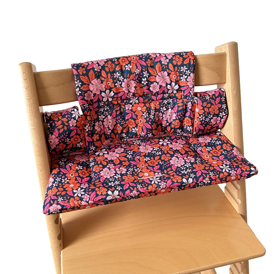 Kussenset voor Stokke Tripp Trapp met bloemenprint (oranje, roze). Zijaanzicht van het kussen op de stoel zonder gebruik van de babyset.