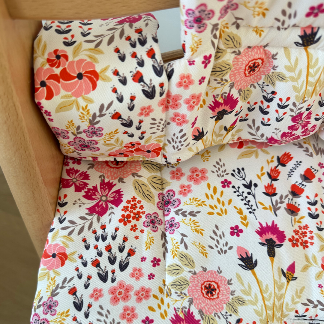 Kussenset voor Stokke Tripp Trapp met bloemenprint (roze). Close up van het kussen op de stoel met gebruik van de babyset.