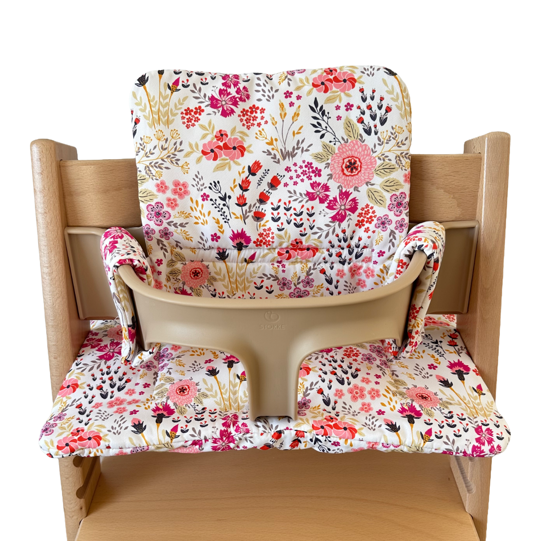 Kussenset voor Stokke Tripp Trapp met bloemenprint (roze). Vooraanzicht van het kussen op de stoel met gebruik van de babyset.