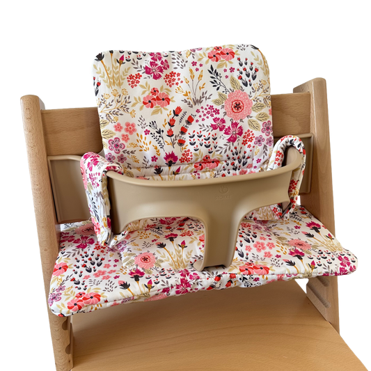 Kussenset voor Stokke Tripp Trapp met bloemenprint (roze). Zijaanzicht van het kussen op de stoel met gebruik van de babyset.