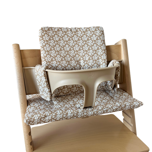 Kussenset voor Stokke Tripp Trapp met minimalistische bloemenprint (bruin, creme). Zijaanzicht van het kussen op de stoel met gebruik van de babyset.