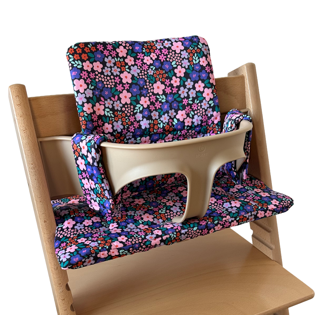 Kussenset voor Stokke Tripp Trapp met bloemenprint (paars, roze). Zijaanzicht van het kussen op de stoel met gebruik van de babyset.