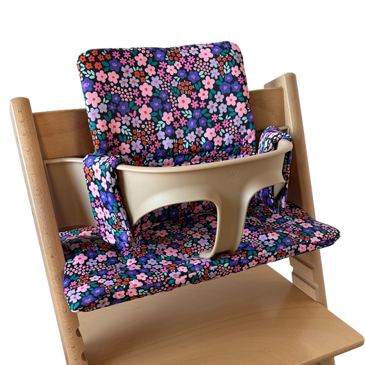 Kussenset voor Stokke Tripp Trapp met bloemenprint (paars, roze). Zijaanzicht van het kussen op de stoel met gebruik van de babyset.