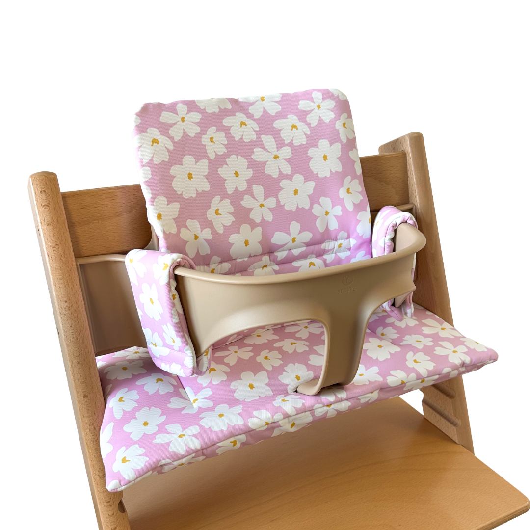Kussenset voor Stokke Tripp Trapp met bloemenprint (roze, wit). Zijaanzicht van het kussen op de stoel met gebruik van de babyset.