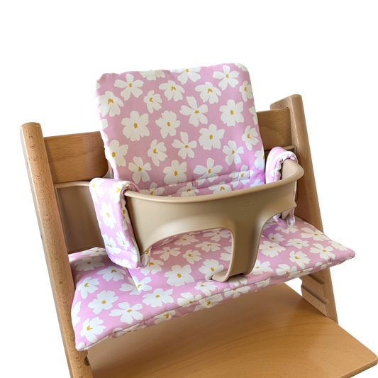 Kussenset voor Stokke Tripp Trapp met bloemenprint (roze, wit). Zijaanzicht van het kussen op de stoel met gebruik van de babyset.