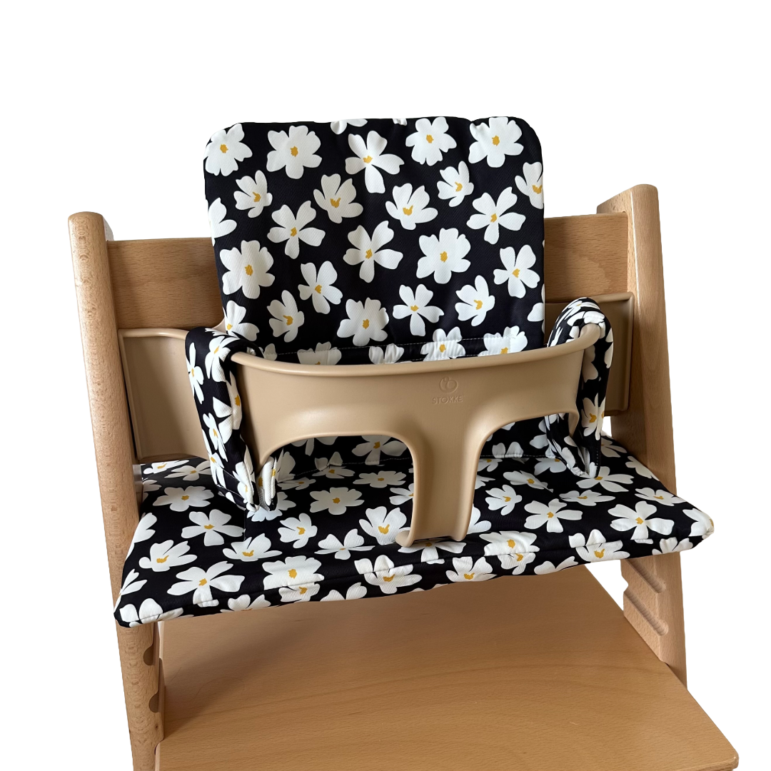 Kussenset voor Stokke Tripp Trapp met bloemenprint (zwart, wit). Zijaanzicht van het kussen op de stoel met gebruik van de babyset.