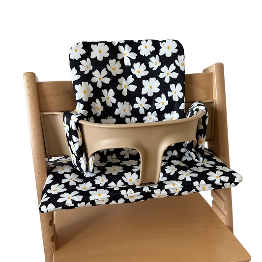 Kussenset voor Stokke Tripp Trapp met bloemenprint (zwart, wit). Zijaanzicht van het kussen op de stoel met gebruik van de babyset.