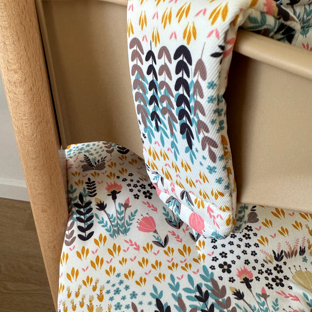 Kussenset voor Stokke Tripp Trapp met print bloemenweide (blauw). Close up van het kussen op de stoel met gebruik van de babyset.