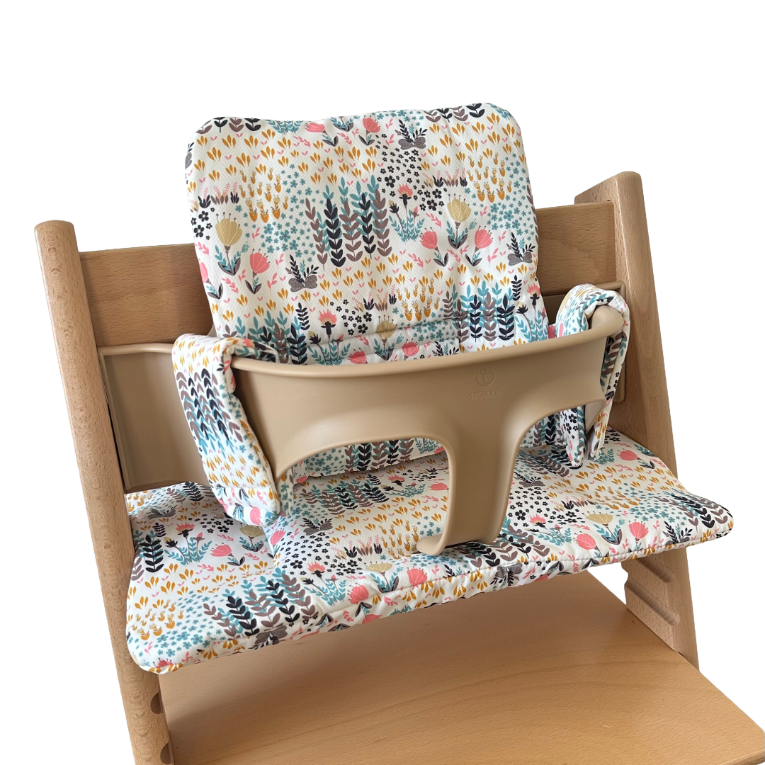 Kussenset voor Stokke Tripp Trapp met print bloemenweide (blauw). Zijaanzicht van het kussen op de stoel met gebruik van de babyset.