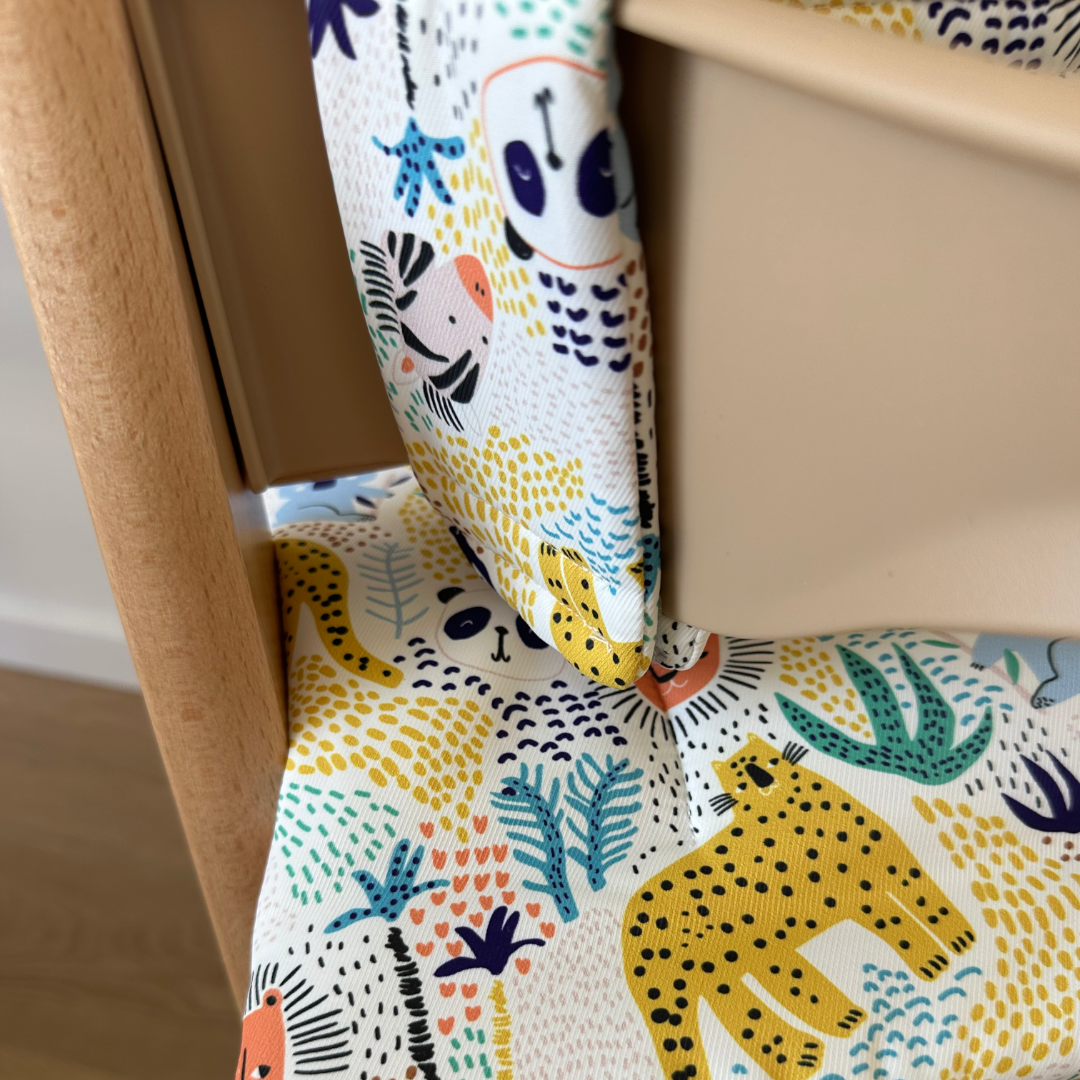 Kussenset voor Stokke Tripp Trapp met dierenprint (koala, panda, leeuw, tijger). Close up van het kussen op de stoel met gebruik van de babyset.