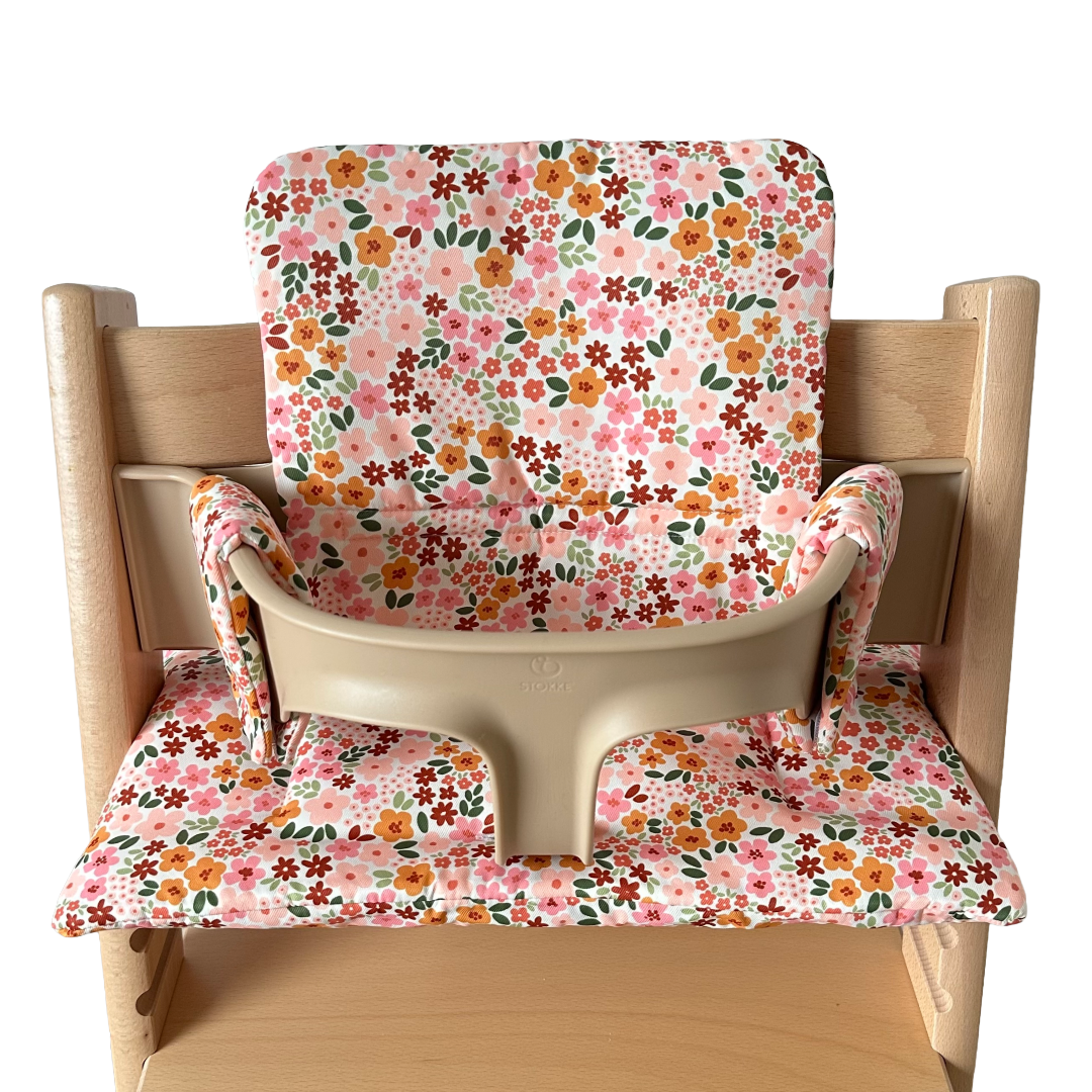 Kussenset voor Stokke Tripp Trapp met herfstbloemen (oranje, rood, roze). Vooraanzicht van het kussen op de stoel met gebruik van de babyset.