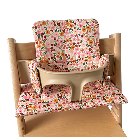 Kussenset voor Stokke Tripp Trapp met herfstbloemen (oranje, rood, roze). Zijaanzicht van het kussen op de stoel met gebruik van de babyset.
