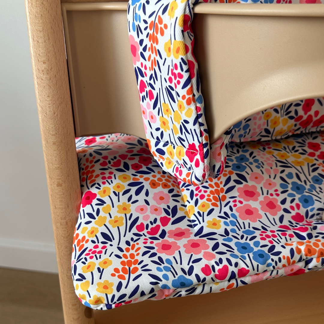 Kussenset voor Stokke Tripp Trapp met kleurrijke bloemen. Close up van het kussen op de stoel met gebruik van de babyset.