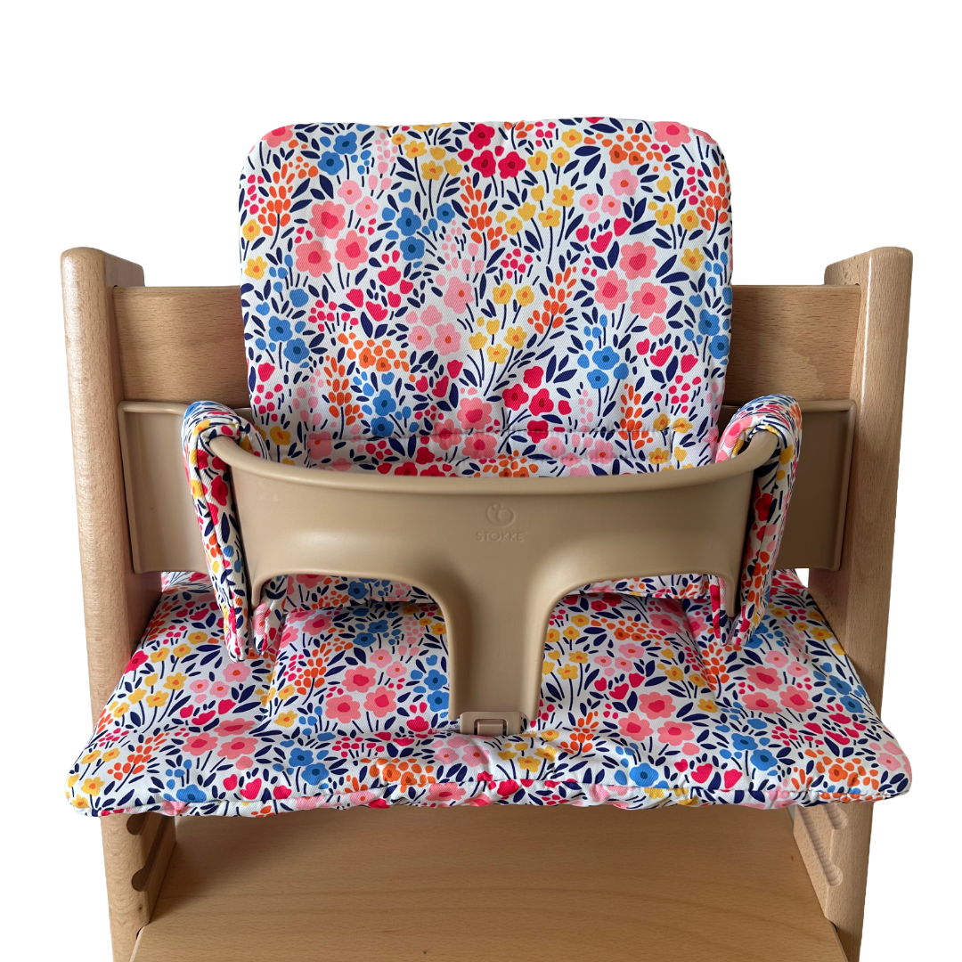 Kussenset voor Stokke Tripp Trapp met kleurrijke bloemen. Vooraanzicht van het kussen op de stoel met gebruik van de babyset.