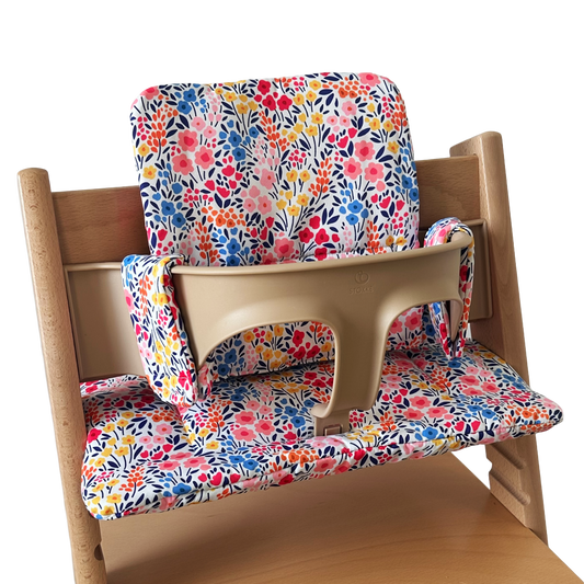 Kussenset voor Stokke Tripp Trapp met kleurrijke bloemen. Zijaanzicht van het kussen op de stoel met gebruik van de babyset.