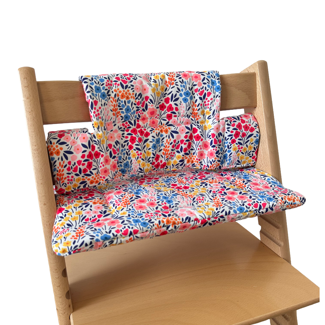 Kussenset voor Stokke Tripp Trapp met kleurrijke bloemen. Zijaanzicht van het kussen op de stoel zonder gebruik van de babyset.