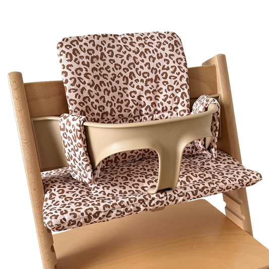 Kussenset voor Stokke Tripp Trapp met luipaardprint. Zijaanzicht van het kussen op de stoel met gebruik van de babyset.
