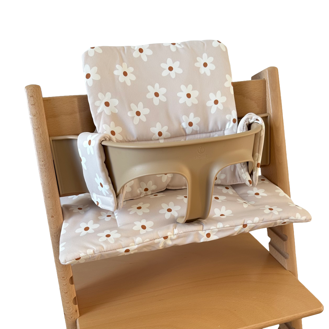 Kussenset voor Stokke Tripp Trapp met print madeliefjes (wit). Zijaanzicht van het kussen op de stoel met gebruik van de babyset.