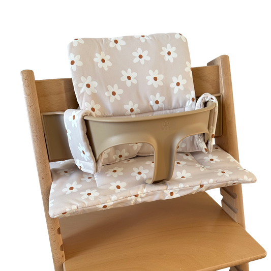 Kussenset voor Stokke Tripp Trapp met print madeliefjes (wit). Zijaanzicht van het kussen op de stoel met gebruik van de babyset.