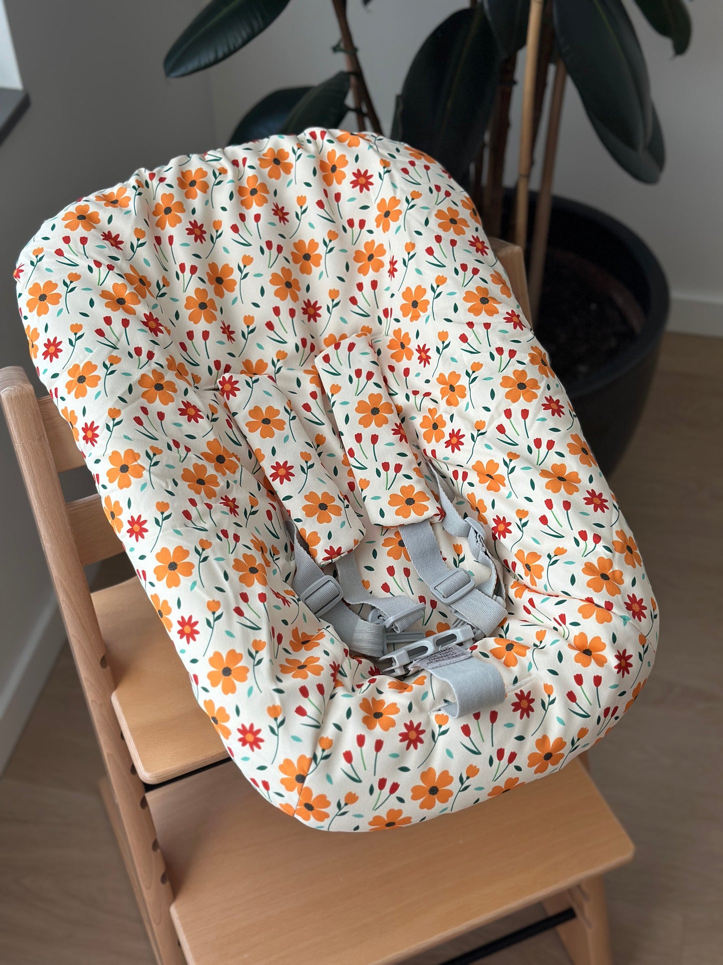 Sfeerfoto van de botergele newborn hoes voor de Stokke Tripp Trapp newborn set met oranje en rode bloemenprint.