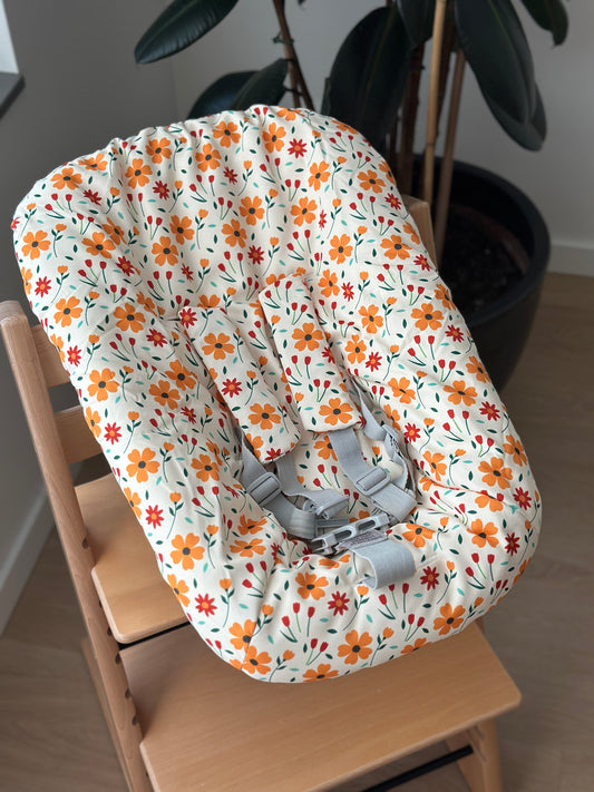 Sfeerfoto van de botergele newborn hoes voor de Stokke Tripp Trapp newborn set met oranje en rode bloemenprint.